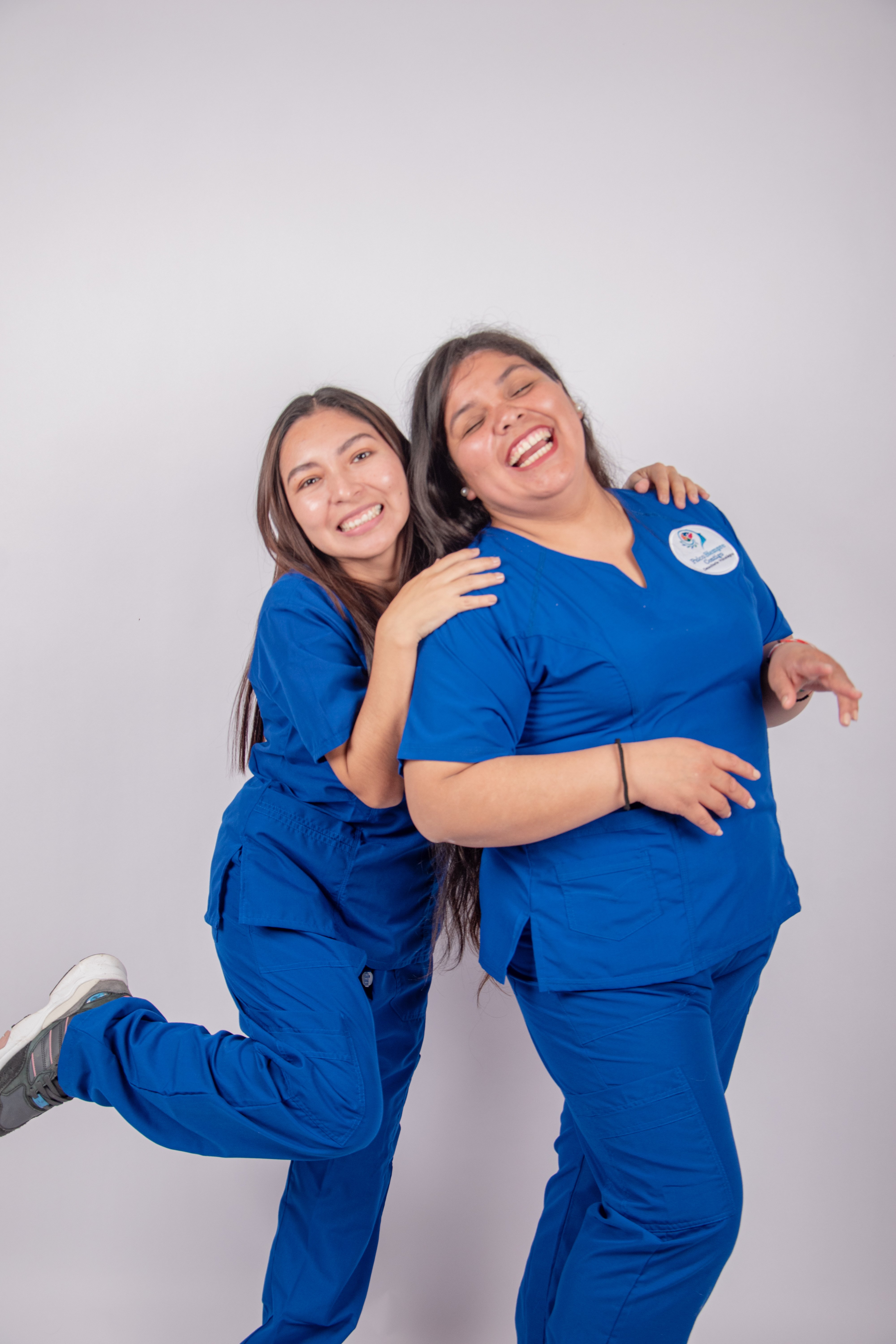 Two nurses laughing together in scrubs